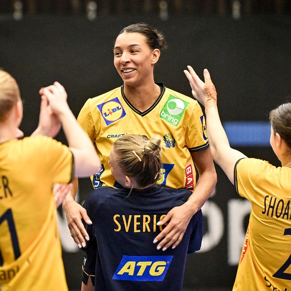 Handbollsspelare i gula tröjor firar och sträcker armarna mot en lagkamrat.