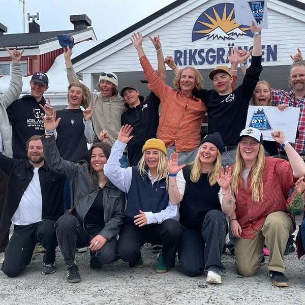 Glada personer poserar med diplom framför entrén till Riksgränsen på vintersäsong.
