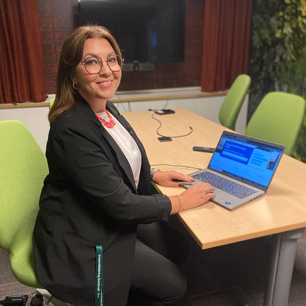 Rektorn på vuxenutbildningen i Sundsvall Jennie Sjögren sitter vid ett bord med en laptop framför sig och vuxenskolans hemsida där en egenutvecklad AI-assistent finns som kan svara på frågor.
