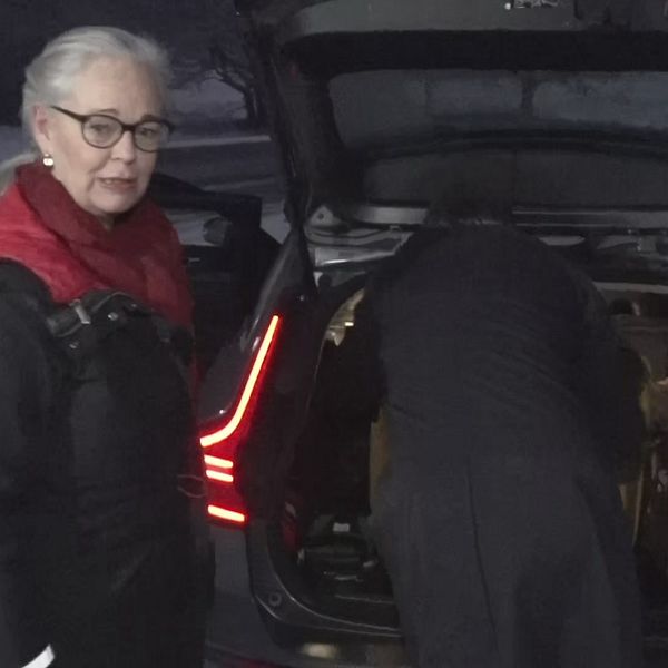 Kvinna står framför bakluckan på bil medan man packar den med väskor