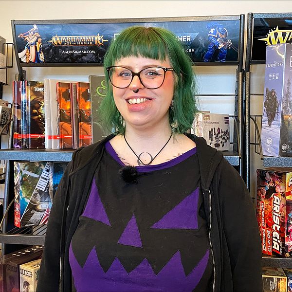 en kvinna framför en vägg med brädspel i en spelbutik