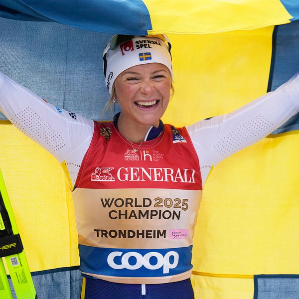 Skidåkare firar med en svensk flagga, bär guldfärgad väst med texten ”World Champion Trondheim”.