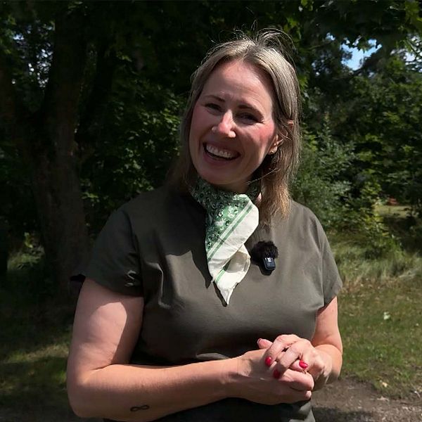 Emmy Ahlstedt (C) står utomhus och pratar i solen.