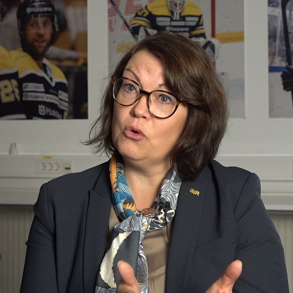 Person i kostym framför hockeybilder på väggen.