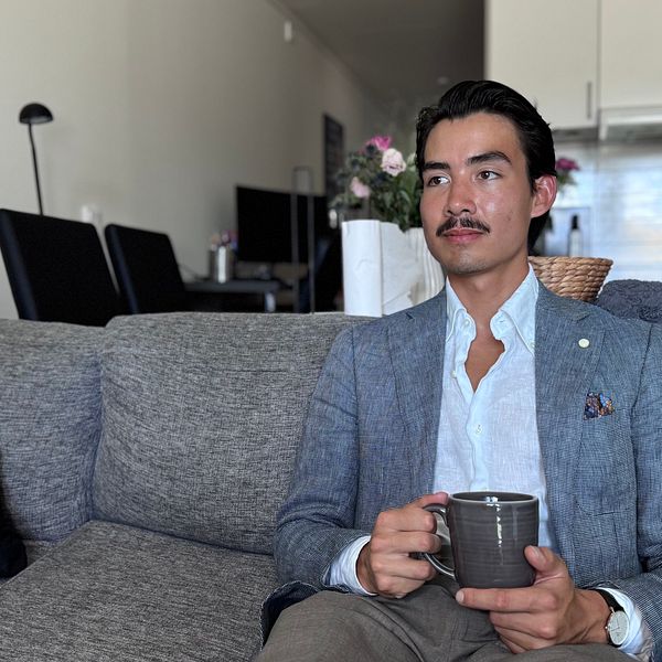 Lukas Lundström sitter i en soffa med en kopp i handen i hemmiljö.