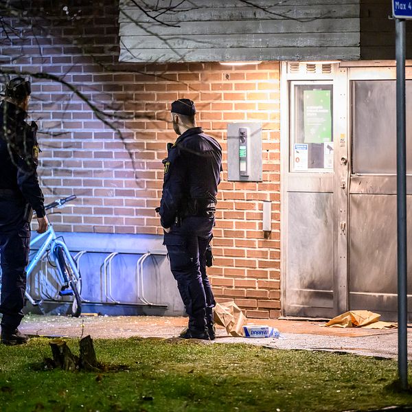 Poliser undersöker en brottsplats vid en tegelbyggnad på natten.