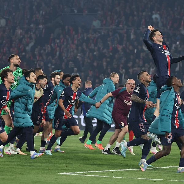 Fotbollsspelare firar seger tillsammans på planen inför jublande publik.
