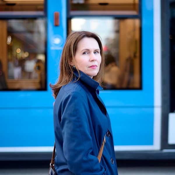 Tiina Laitila Kälvemark seisoo sinisen raitiovaunun edessä.