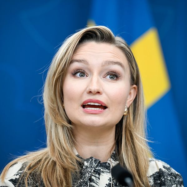 Ebba Busch framför en svensk flagga.