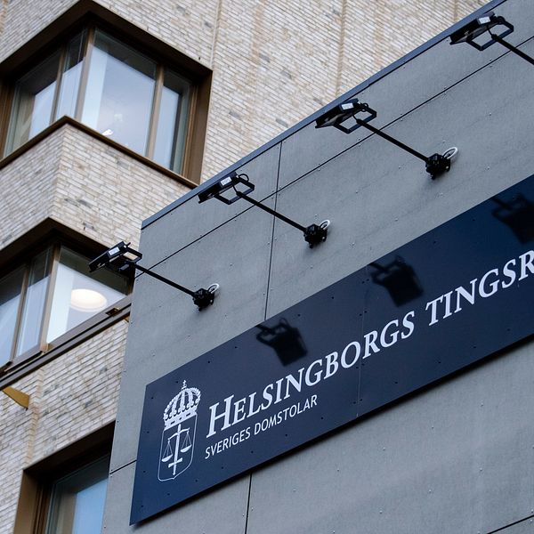 Skylt med texten ”Helsingborgs Tingsrätt” på en modern byggnad med glasfönster och tegelväggar.