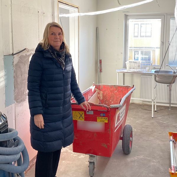 Bild på kvinna i blå jacka inne i en lägenhet som renovera i Motala.