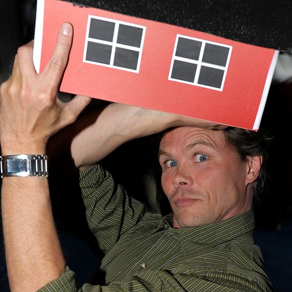 konstnären Mikael Genberg med ett litet hus ovanför huvudet