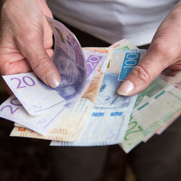 Kvinna visar sedlar och håller dem som en solfjäder i handen.