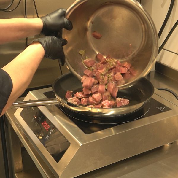 kött hälls ner i en stekpanna