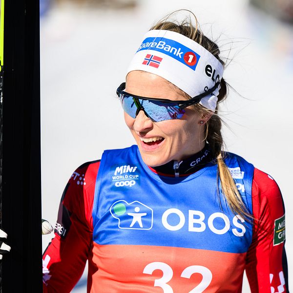 Skidåkare i tävlingsdräkt håller en skida; nummerlapp 32.