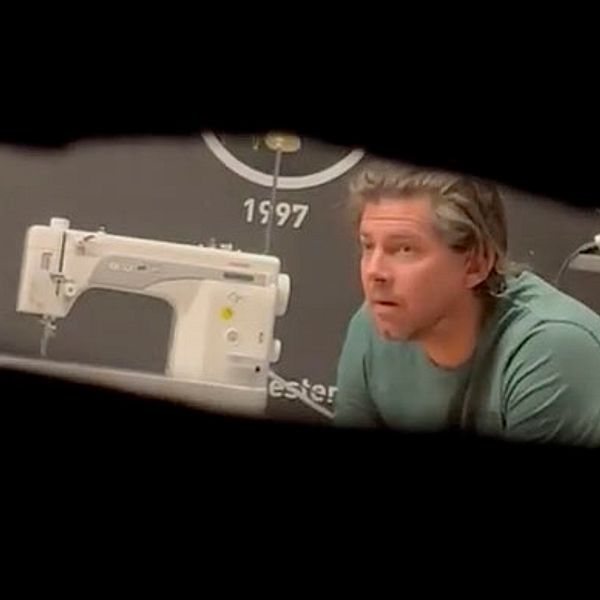Symaskin på skrivbord, årtal 1997 synligt på väggen i bakgrunden.