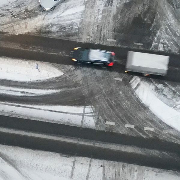 En bil med ett släp på en snöig väg. Bilden är tagen från ovan med en drönare.