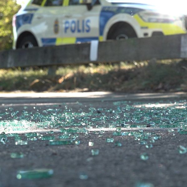 Glas på marken efter en skjutning i Årby. En polisbil står i bakgrunden.