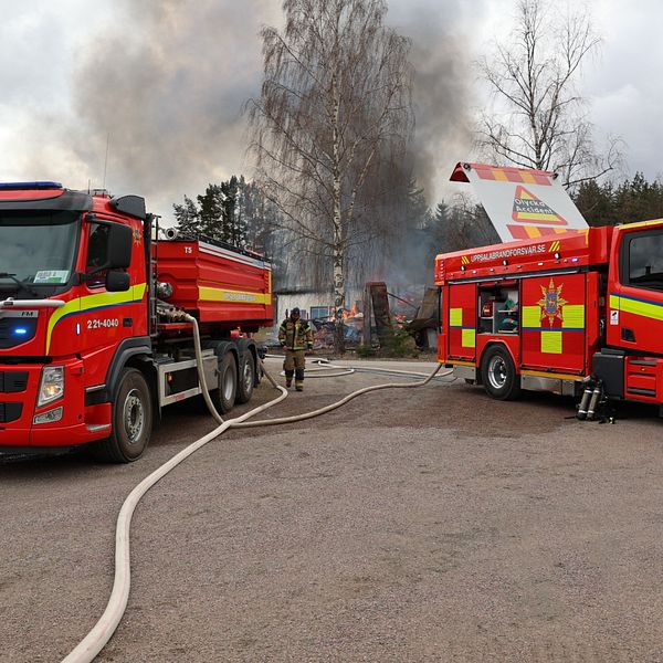 Två brandbilar framför en brinnande ladugård