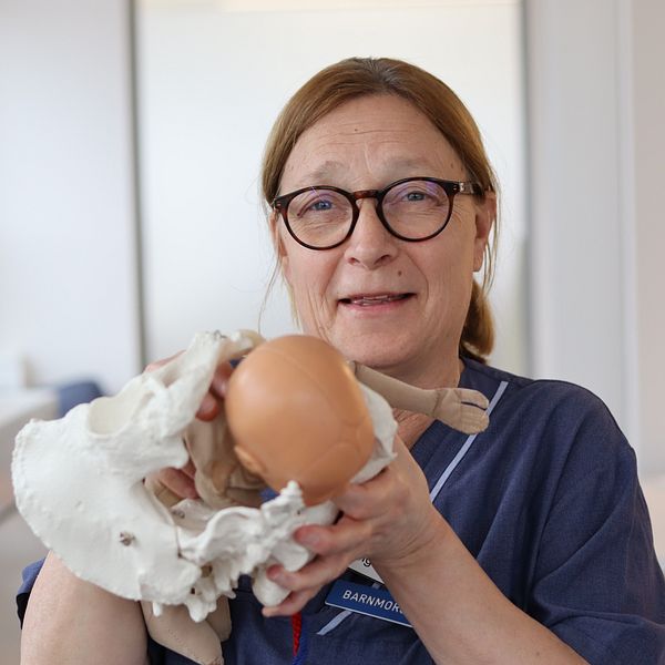 En barnmorska visar upp med hjälp av en docka hur en förlossning går till.