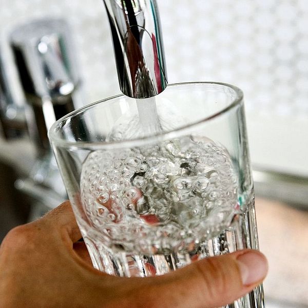 Glas fylls med vatten från kran.