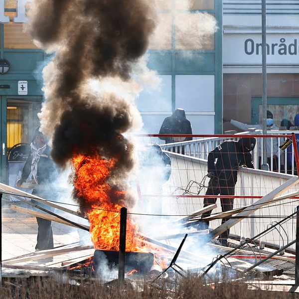 Personer gör en barikad med brinnnade bildäck och andra föremål vid Ringdansen centrum, i samband med upplopp i Navestad i Norrköping på påskdagen
