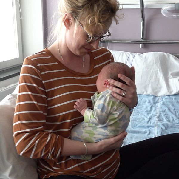 Person i randig tröja håller en baby på ett sjukhusrum på Lycksele BB.
