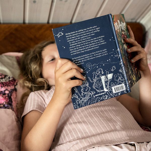 Ett barn läser en bok i en säng