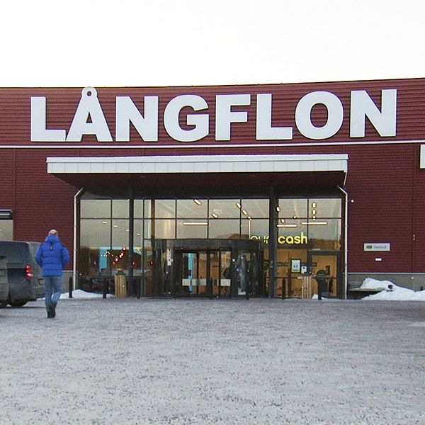 Ingången till köpcentret Långflon, med parkerade bilar och en person som går mot dörren.