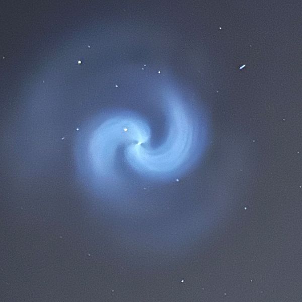 Stjärnhimmel med blå spiralformad ljusformation i centrum.