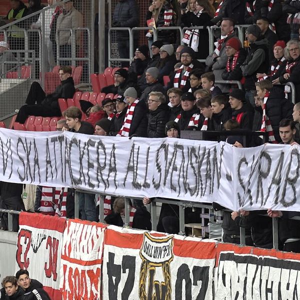 En stor grupp supportrar på läktaren håller upp en banner med texten ”Vi ska inte ge er all svenskan” följt av ”GFA 188”. Många av dem bär lagets färger och sjunger, vilket skapar en intensiv stämning under matchen. Bannerna i bakgrunden förstärker känslan av klubbsupport.
