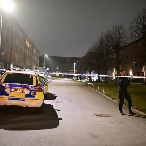 Polisbil och avspärrning vid bostadsområde på kvällen.