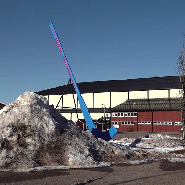 Bandyklubba i storformat framför bandyhall