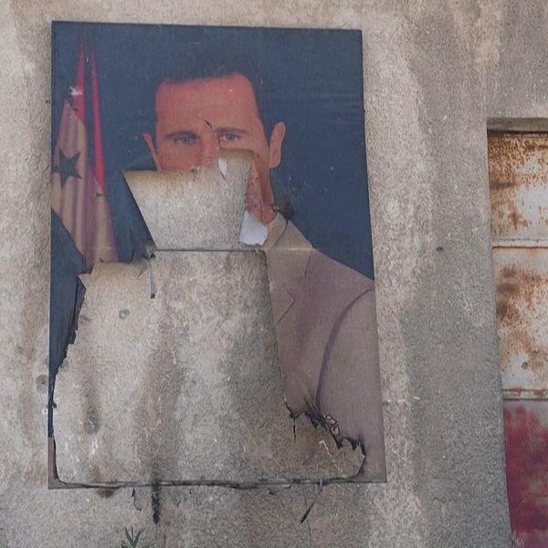 Porträtt av Bashar al-Assad på sliten vägg i Syrien