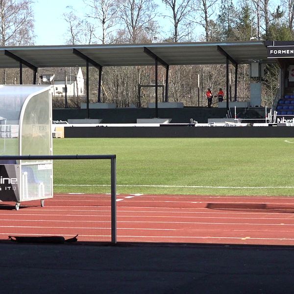Tom fotbollsstadion med avbytarbänk och tomma läktare.