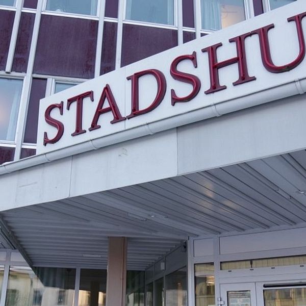 Entré till stadshus med skylt i stora röda bokstäver.
