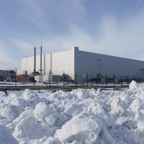 Stor fabrik i vinterlandskap med snö framför byggnaden.