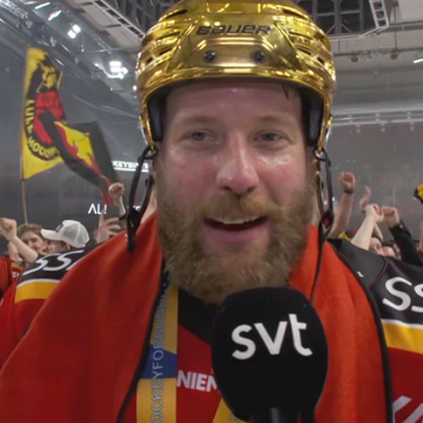 Hockeystjärna med guldhjälm intervjuas på isen, fans firar i bakgrunden.