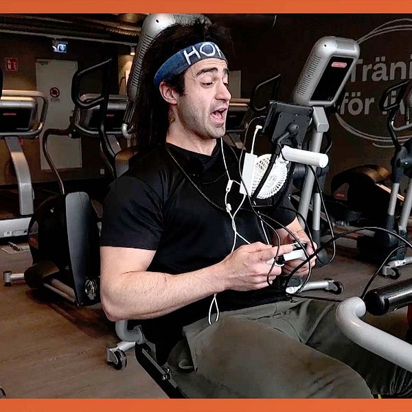 Person tränar på motionscykel på gym, omgiven av träningsmaskiner.