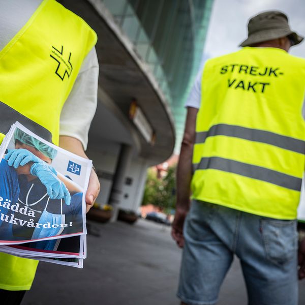 En strejkande vårdarbetare håller i en pamflett.