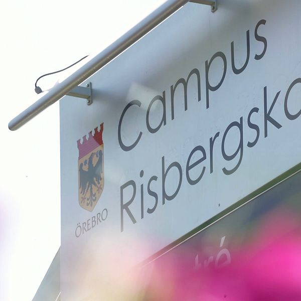 Skylt för Campus Risbergska med suddiga rosa blommor i förgrunden