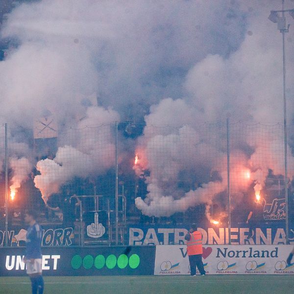 Fotbollsfans bränner pyroteknik och skapar tätt rökmoln i publikhavet.