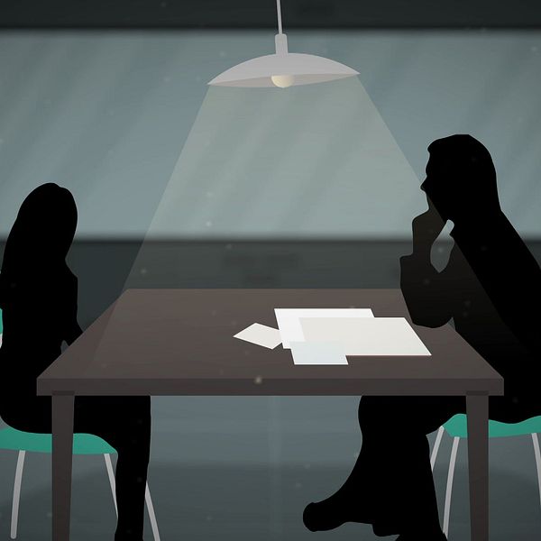 Två silhuetter av personer sitter vid ett bord under en stark lampa, med papper framför dem, vilket ger en känsla av en konversation eller förhör.