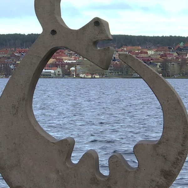 Skulptur vid Vättern med Huskvarna stadssiluett i bakgrunden.
