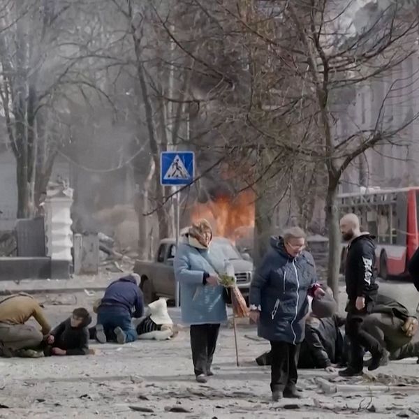 Människor i kaos på gata efter explosion, enkel bild. Eld och skadade synliga i bakgrunden.