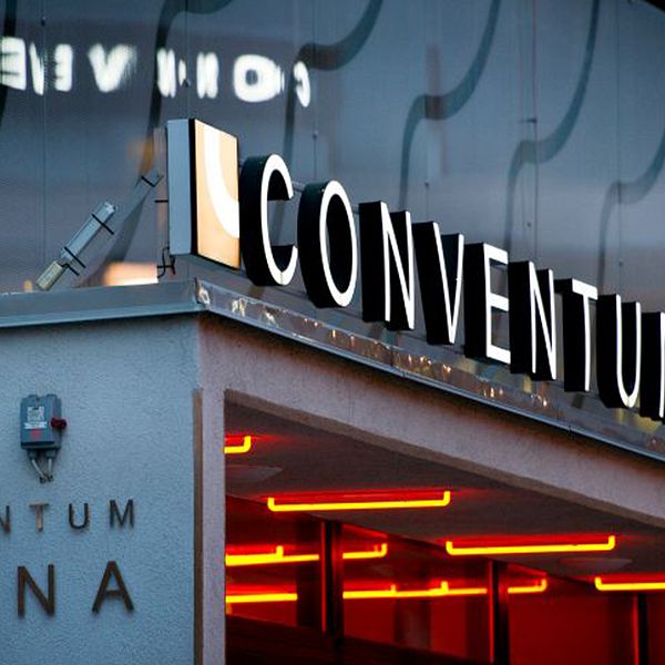 Ingången till Conventum Arena med upplyst skyltskrift och röda lampor under taket.