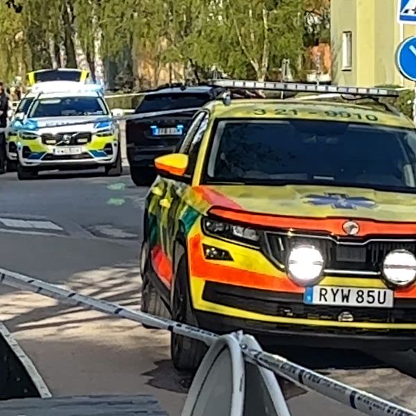 Ambulansfordon och polisbil på avspärrad gata i bostadsområde.