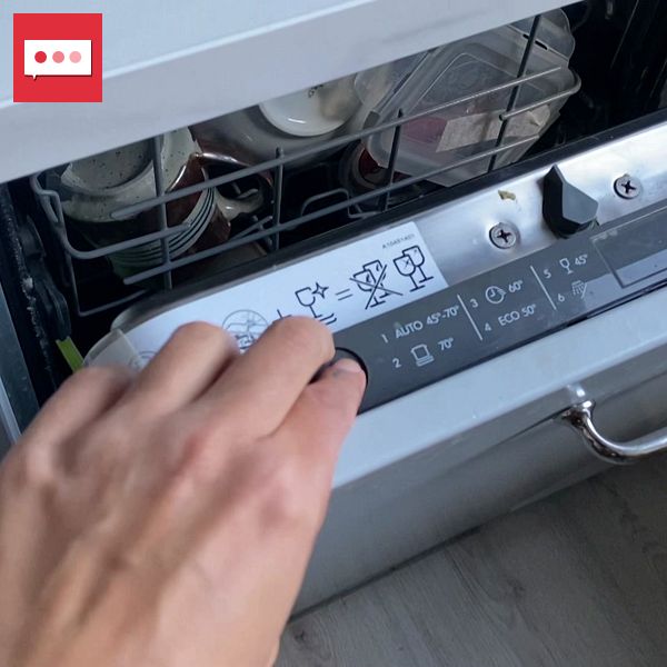 En hand trycker på en diskmaskin