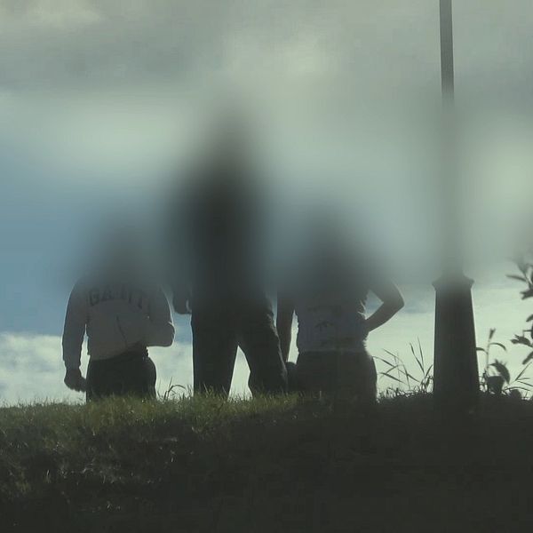 Tre suddiga personer står på en kulle mot himlen