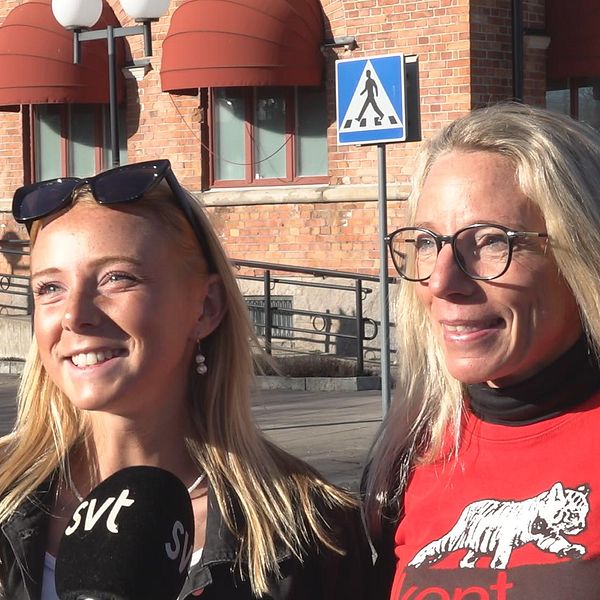 Två kvinnor intervjuas av SVT framför en tegelbyggnad med röda markiser.